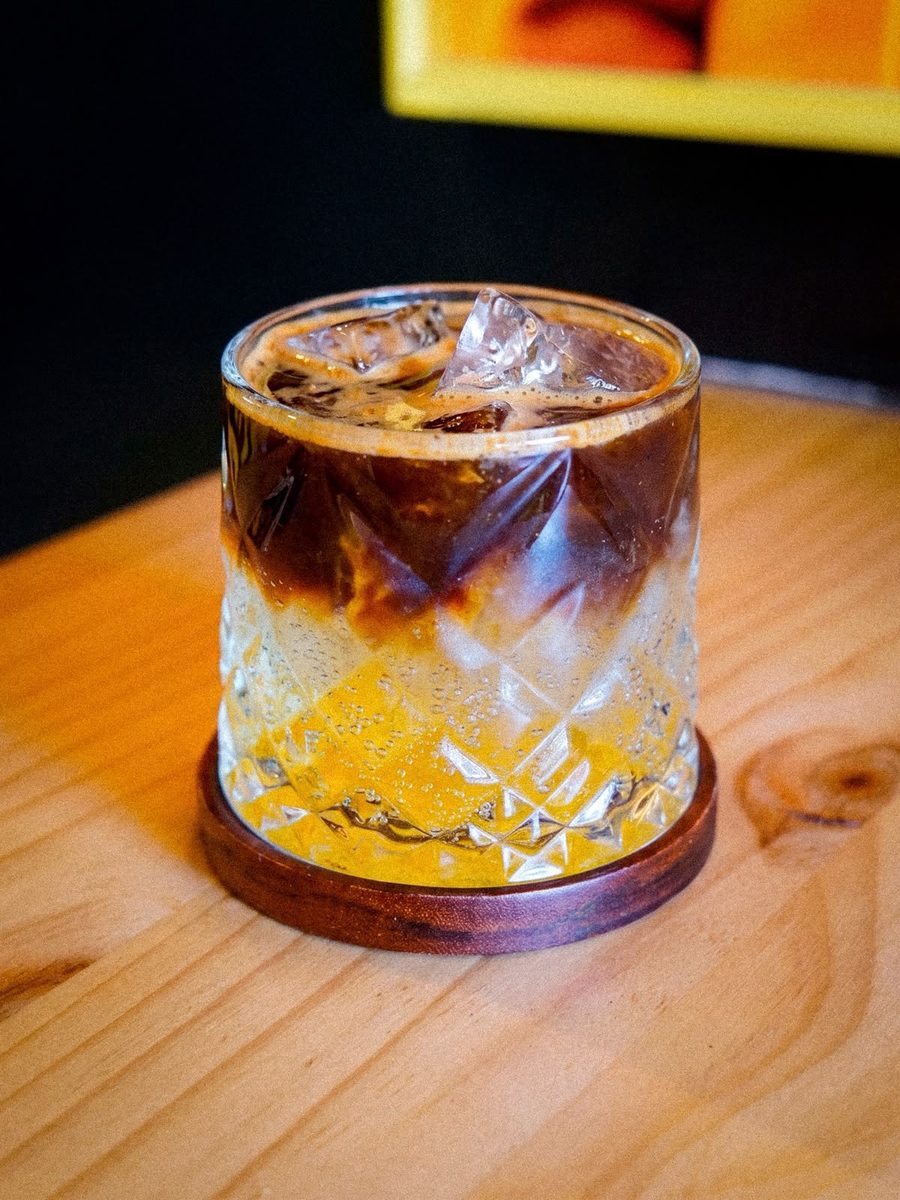 Espresso tonic en vaso labrado, sobre una mesa de madera